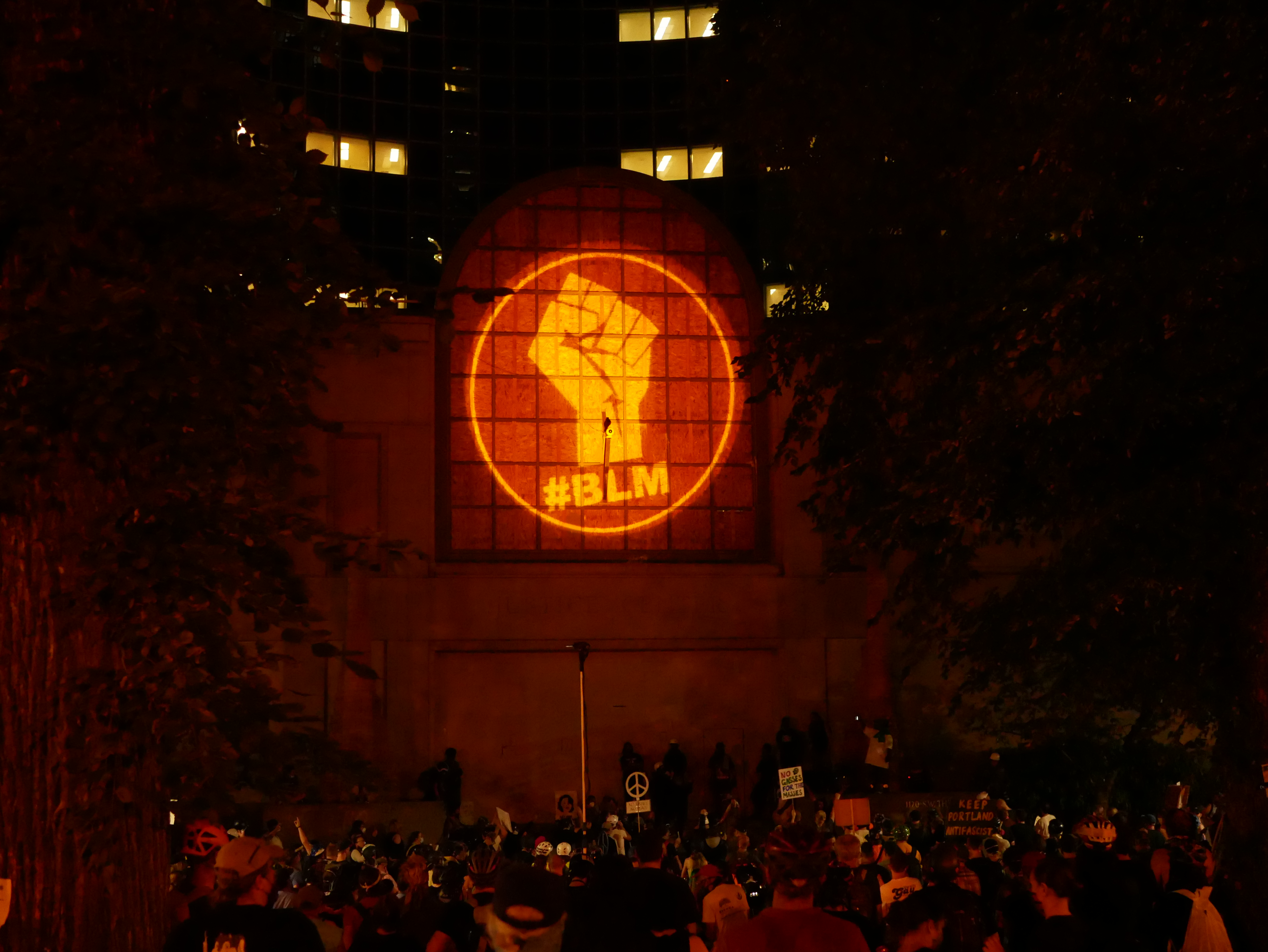 Photograph of a BLM fist projected onto the side of a building.