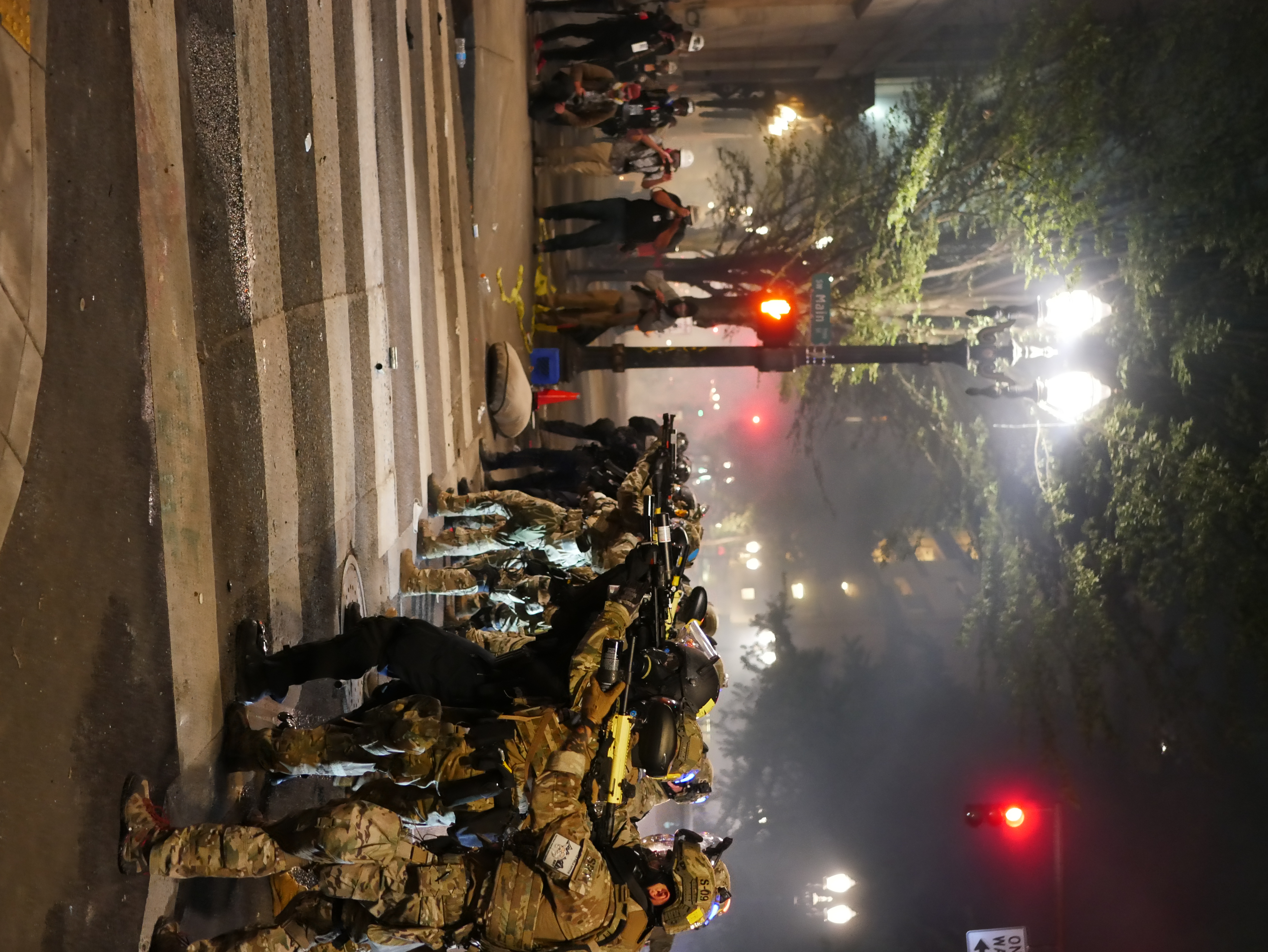 Photograph of a standoff of police officer guns raised, dressed in full camouflage protective gear on the streets of downtown PDX.